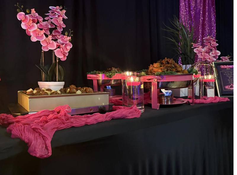 Flavor and Flair Catering buffet with chafing dishes, hot wings, and pink floral decor