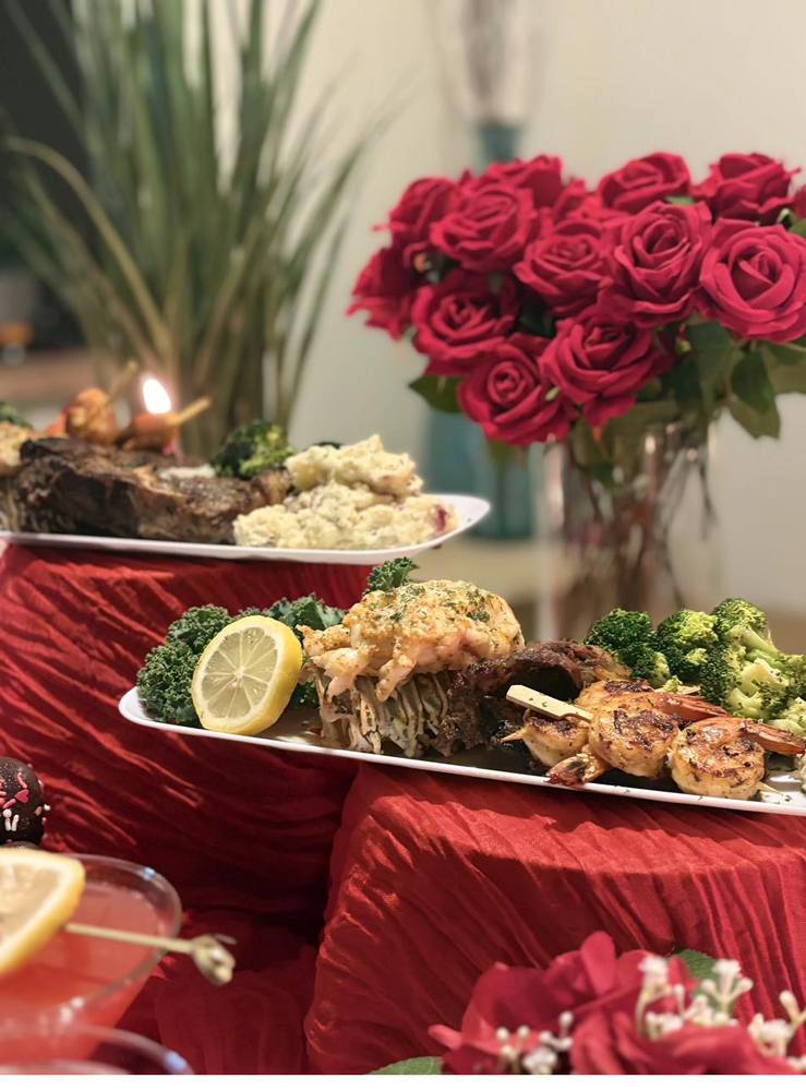 Flavor and Flair Catering romantic dinner with steak, lobster, and red rose centerpiece